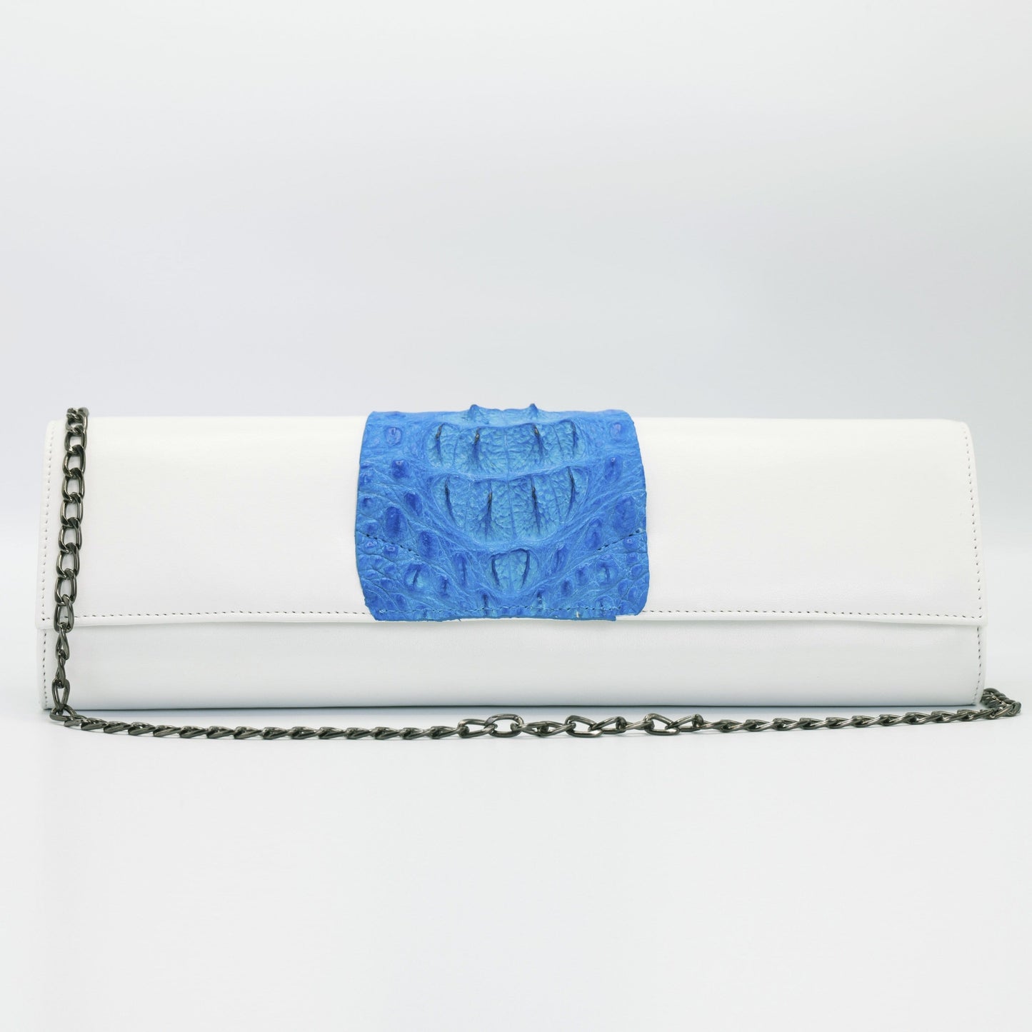 Blue and white Kate crocodile and leather clutch. Handcrafted from Italian saffino leather. Sustainably sourced crocodile ascent, magnetic closure, interior pocket, and removable shoulder strap with a 22” drop.